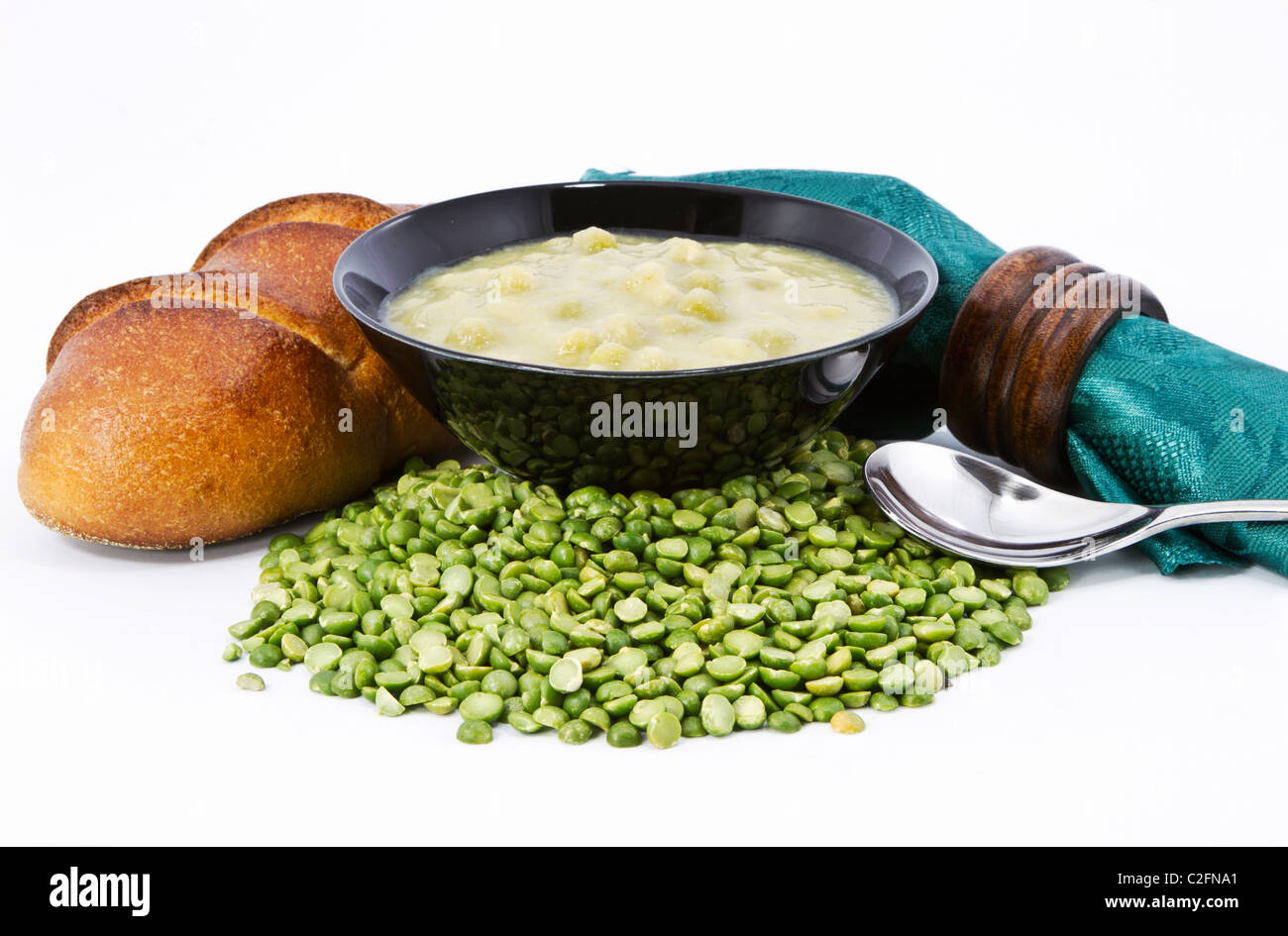 Erbsensuppe in schwarz Schüssel mit frischen Laib Brot, grüne Serviette und braunen Holz Serviettenring auf getrocknete Erbsen Zutat. Stockfoto