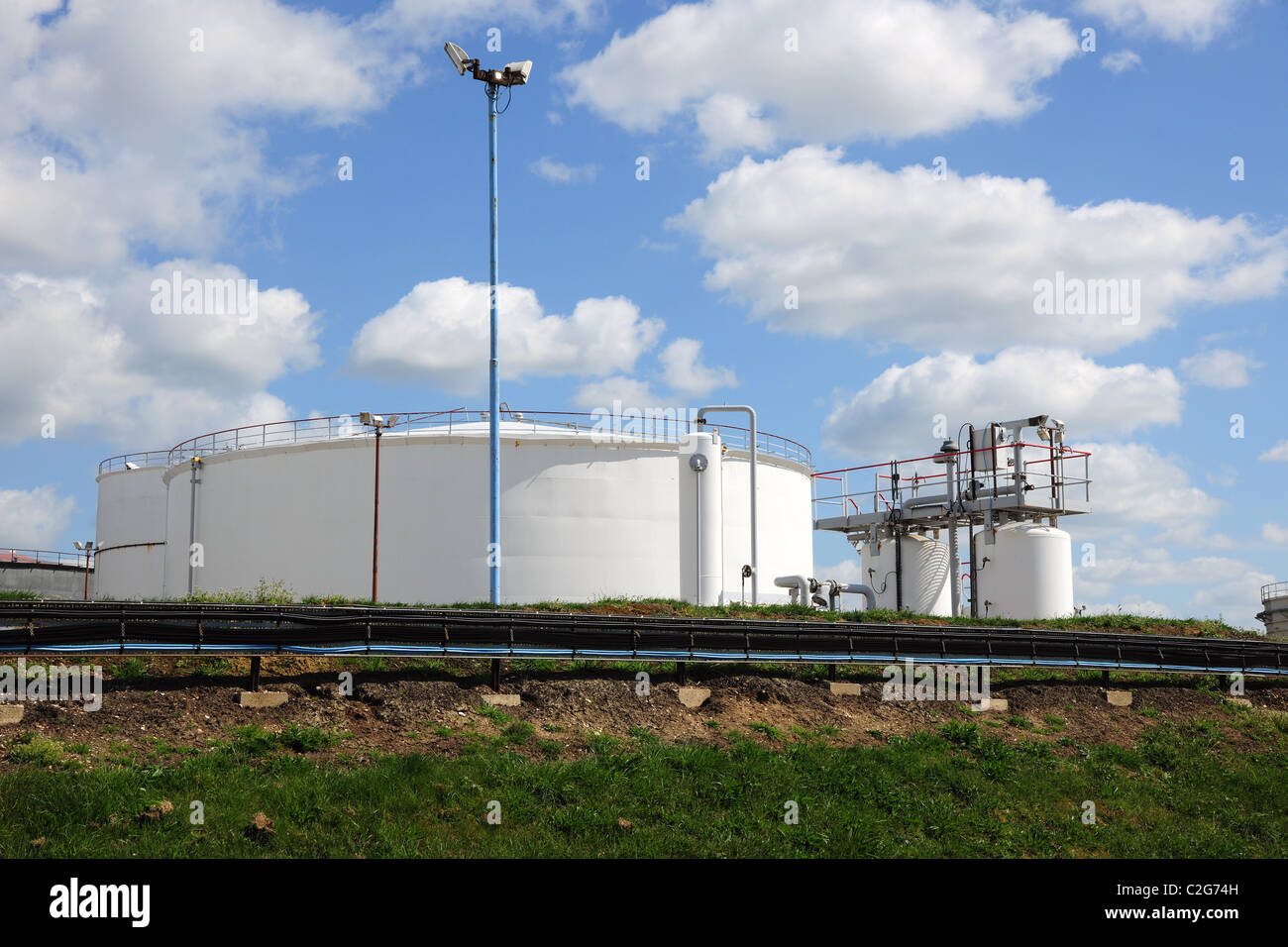 Öltanks in einer Raffinerie vor einem bewölkten blauen Himmel. Stockfoto