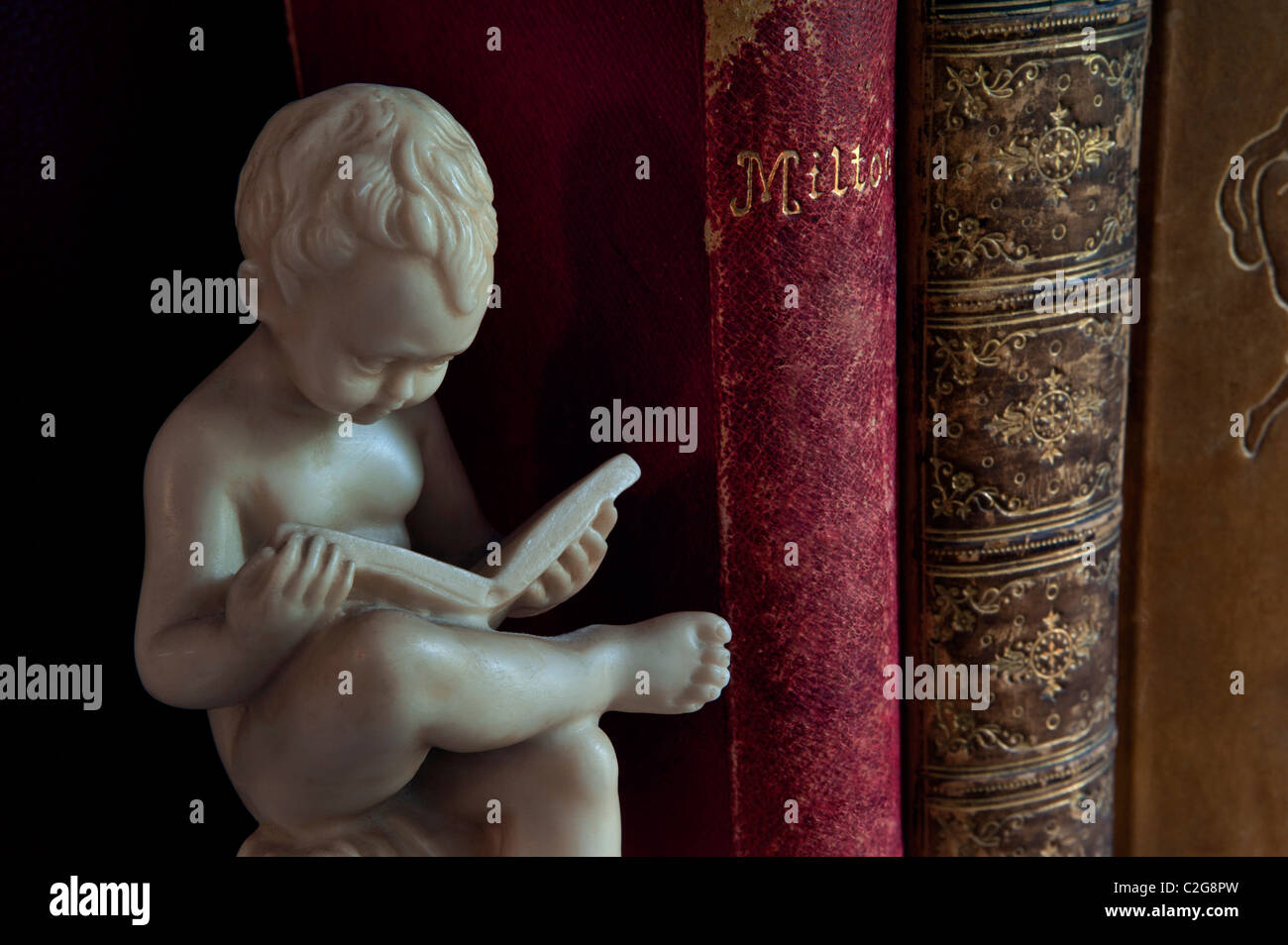 Antiquarische Bücher lesen Klassiker Statue der Junge neben klassischen Leder gebunden Bücher einschließlich historischer John Milton's Paradise Lost poetische Stockfoto