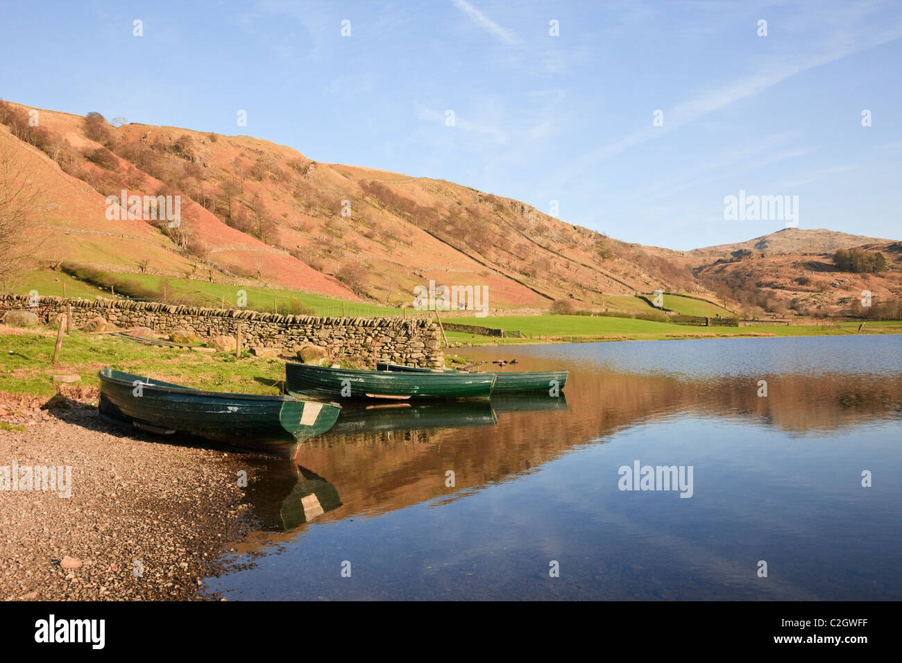 Zwei Boote und Reflexionen des Fells in Watendlath Tarn in der Lake District National Park im frühen Sommer. Watendlath, Cumbria, England, Großbritannien Stockfoto
