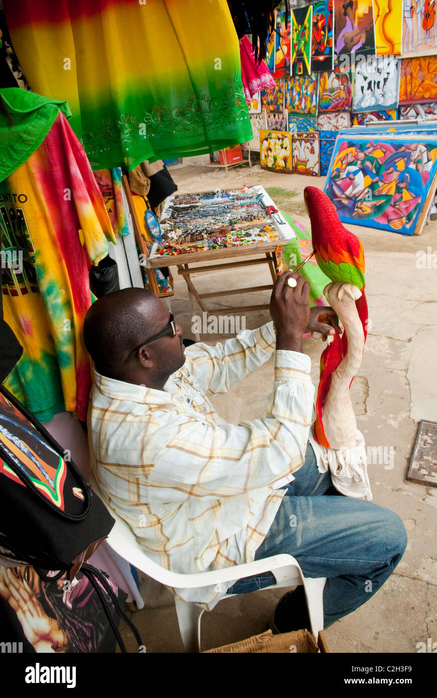 Künstler 'Glen' Malerei einen geschnitzten hölzernen Vogel auf dem Handwerksmarkt Negril, in der Nähe von Westmoreland Negril Stadtzentrum, Negril, Jamaika Stockfoto