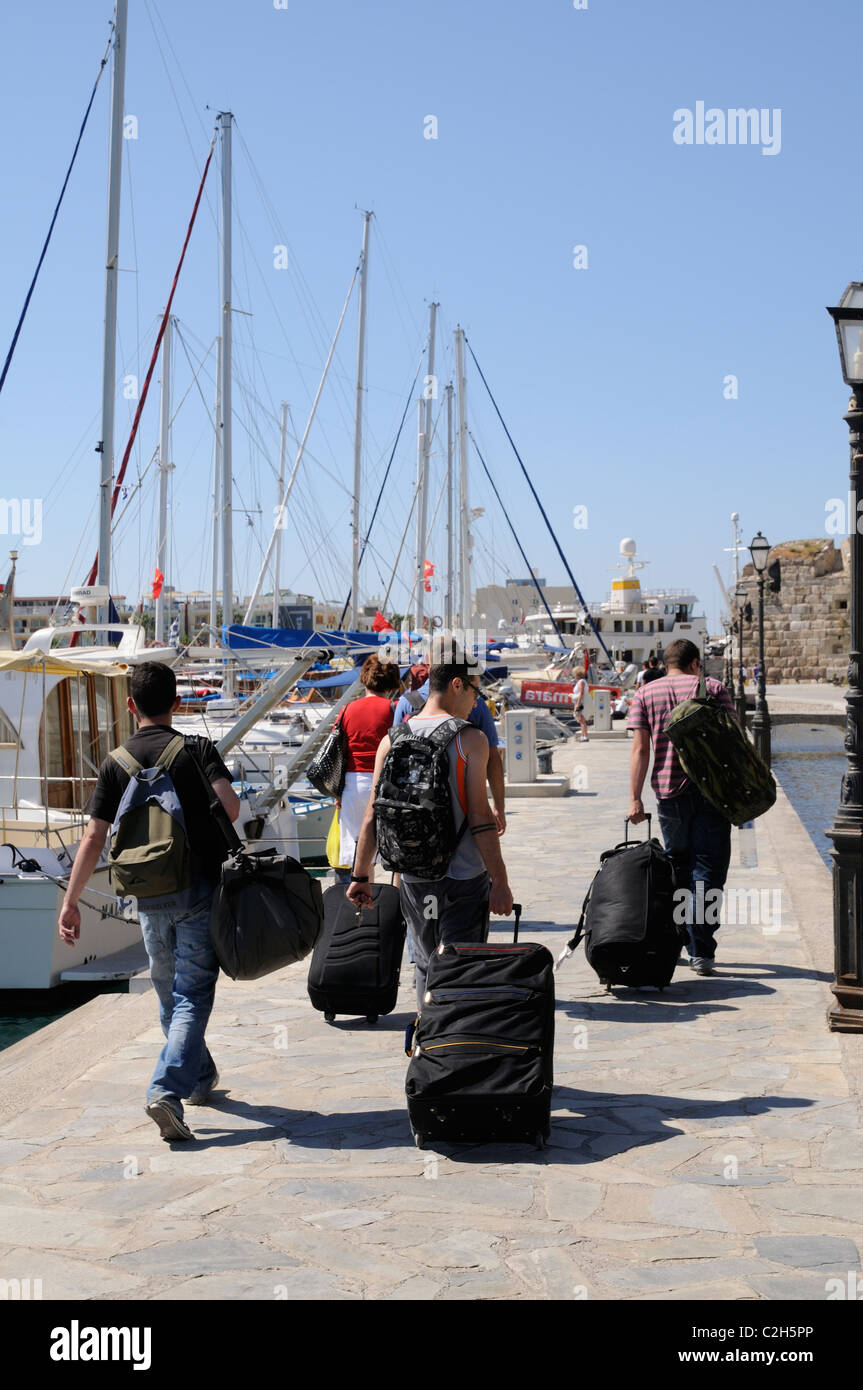Reisende schleppen ihr Gepäck zum Fährhafen am Hafen von Kos-Stadt auf der Insel Kos Griechenland Stockfoto