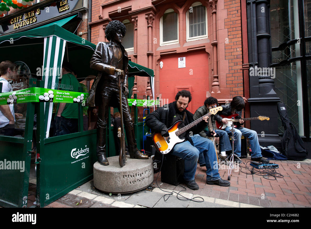 Musik Spieler neben der Statue des Musikers Phil Lynott von der Band Thin Lizzy. St Patricks Day in Dublin Irland Stockfoto