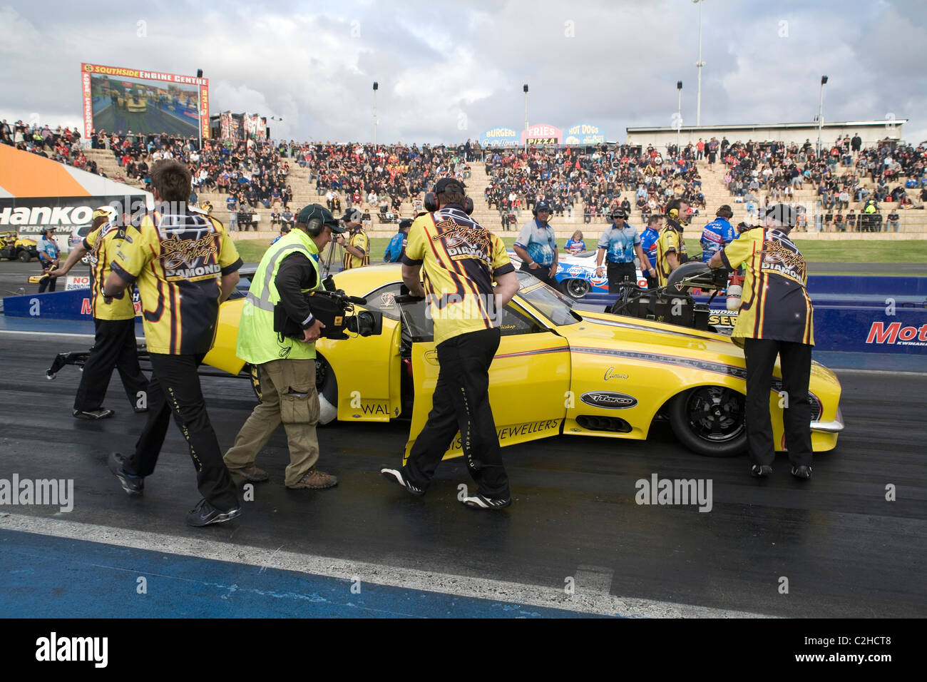 Stuart Bishop, führenden australischen Drag Racer ist umgeben von seiner Boxencrew und Medien, während er in seinem Camaro-Rennwagen sitzt Stockfoto