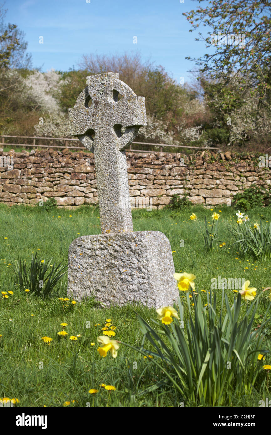 Kreuz Grabstein mit Narzissen im Friedhof von St. Mary Church, Powerstock im April Stockfoto