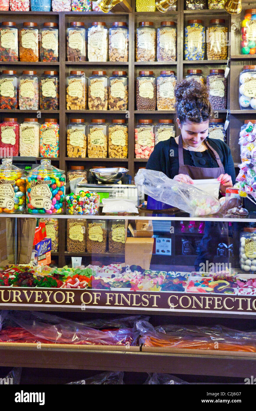 Innere der Süßwarenladen oder Konditorei zeigt Display Regale von süßen Gläsern und einer weiblichen Verkäuferin Packung Süßigkeiten Stockfoto
