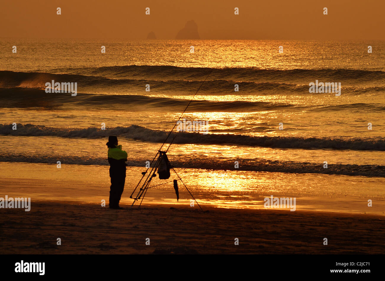 Warten auf einen Fisch. Ein Strand-Angler auf Perranporth Strand bei Sonnenuntergang Stockfoto