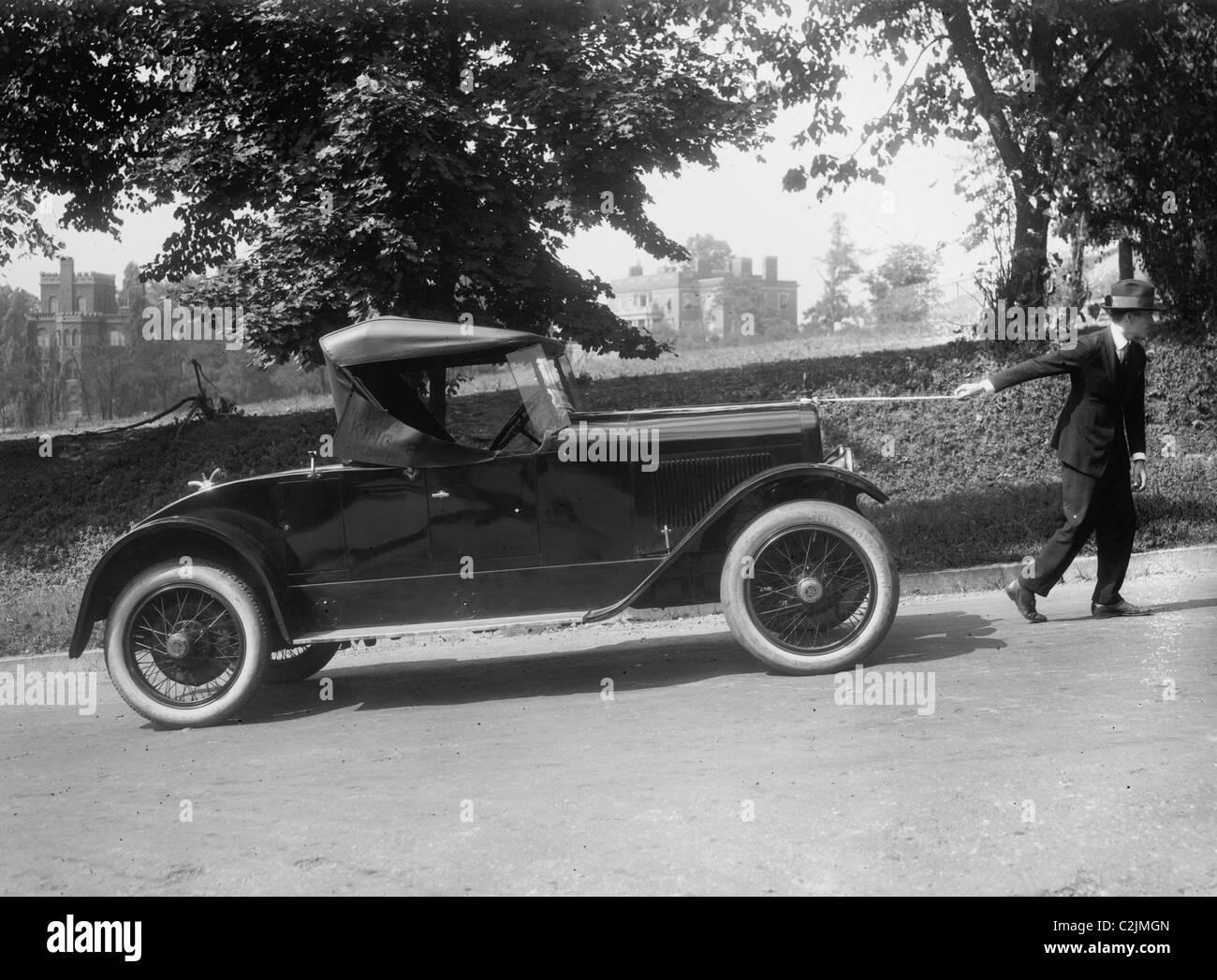 Mann sieht geeignet, wie er ist ein Coupé auf einer schiefen Ebene durch eine Zeichenfolge ziehen Stockfoto