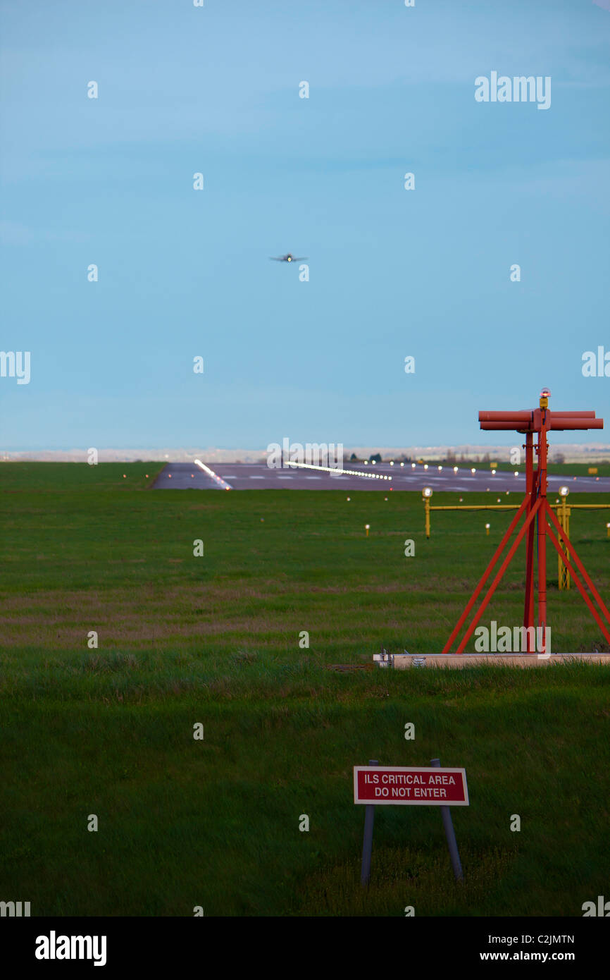Ein Flugzeug kommen, um in der Ferne auf einem Flughafen zu landen, an einem hellen Sommertag Stockfoto