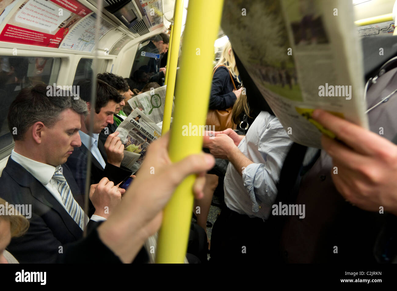 Passagiere, die Zeitung in einer überfüllten U-Bahn lesen Rohr Zug, London, England, UK Stockfoto