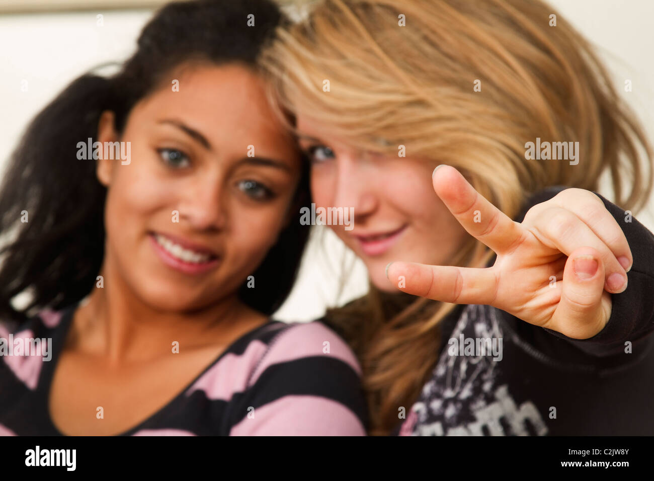Zwei hübsche, weibliche Teenager, eine durchlöchern Sie zwei Finger auf die Kamera. Stockfoto