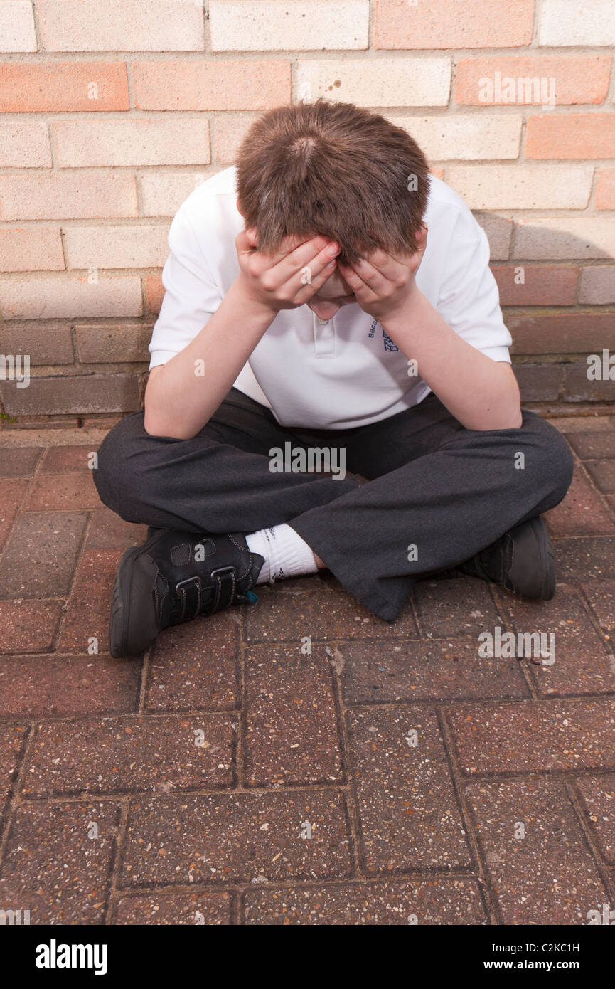 Ein MODEL Release Bild eines elf Jahre alten Jungen auf der Suche deprimiert im Freien tragen seine Schuluniform im Vereinigten Königreich Stockfoto