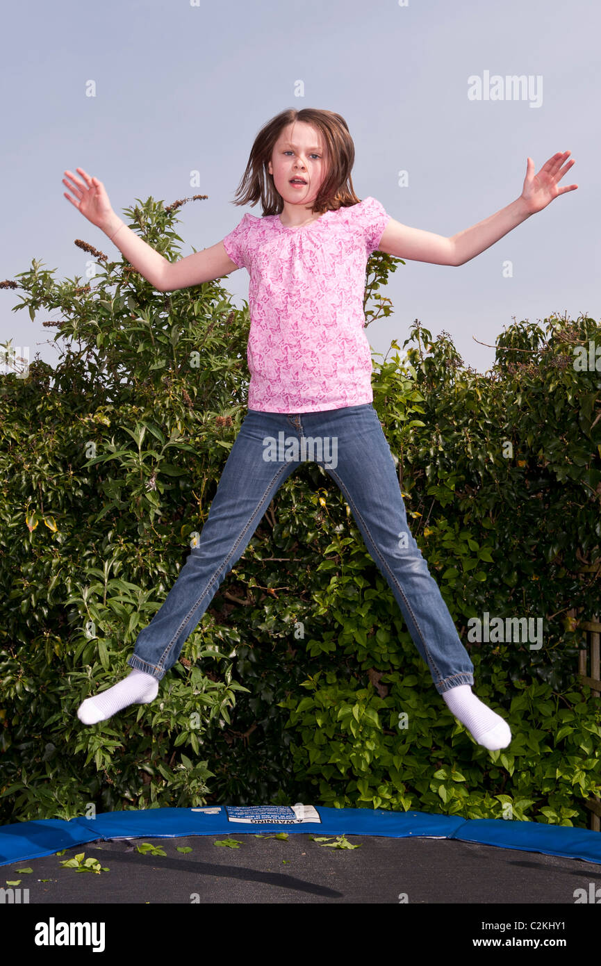 Ein MODEL Release Bild von ein neun Jahre altes Mädchen im Freien auf einem Trampolin im Vereinigten Königreich Stockfoto