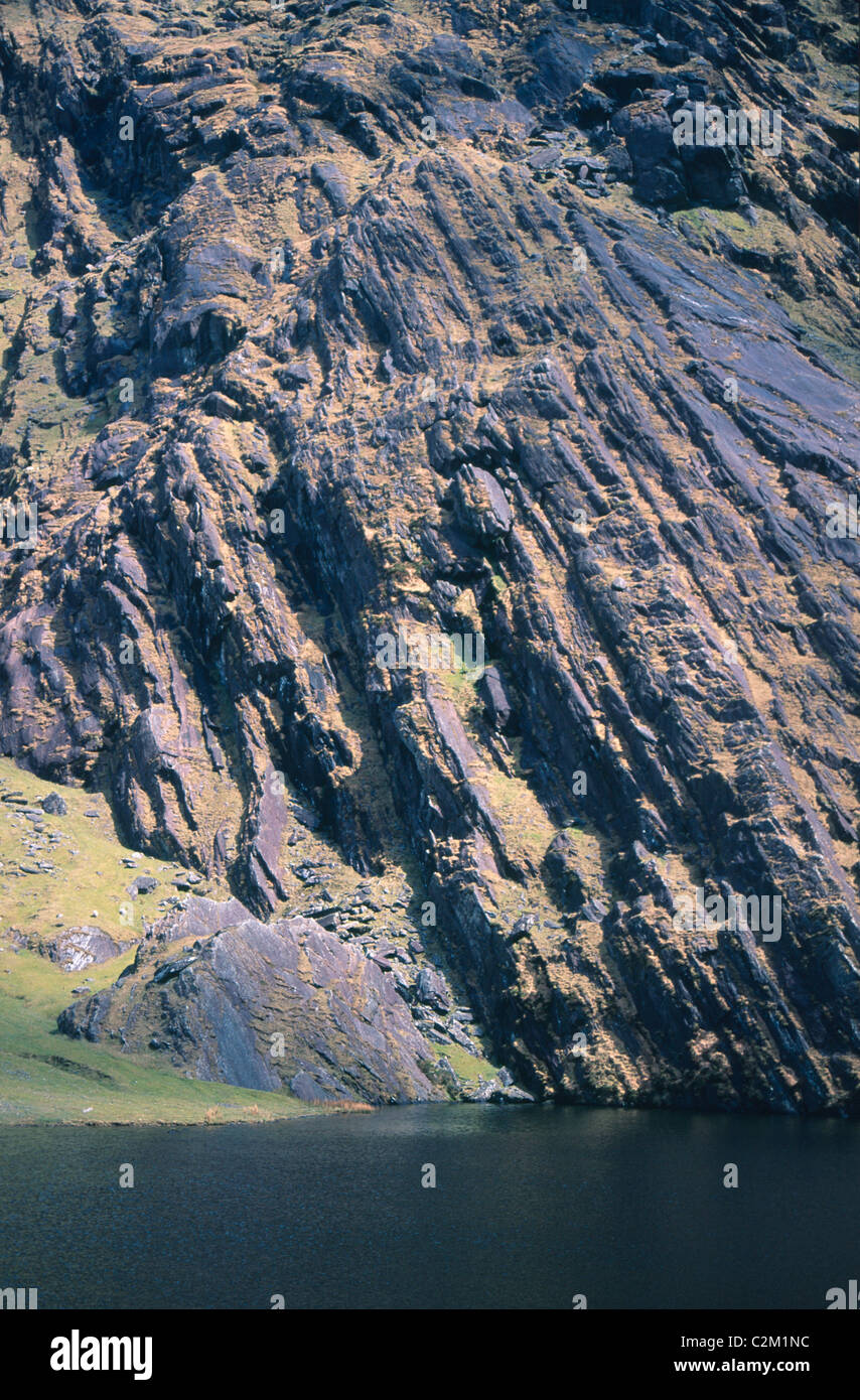 Gefaltete Sandsteinfelsen an einem See im Knockmoyle Coomavoher, Berg, County Kerry, Irland. Stockfoto