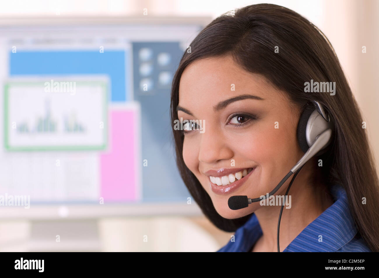 Lächelnde Frau mit Kopfhörer und Computer-monitor Stockfoto