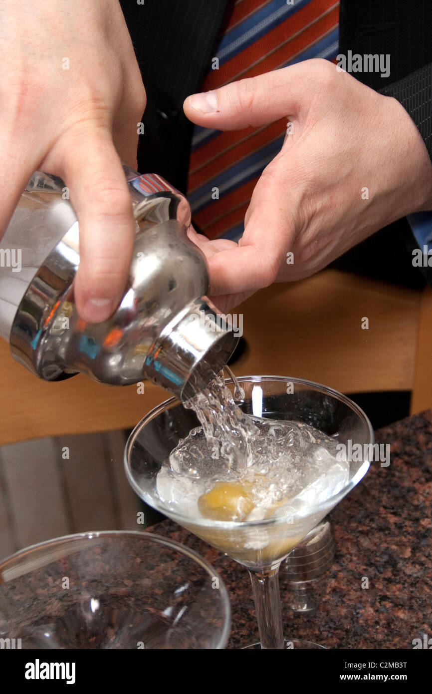 Man gießt einen Gin Martini aus einem Shaker in Stielgläser mit Oliven. St Paul Minnesota MN USA Stockfoto