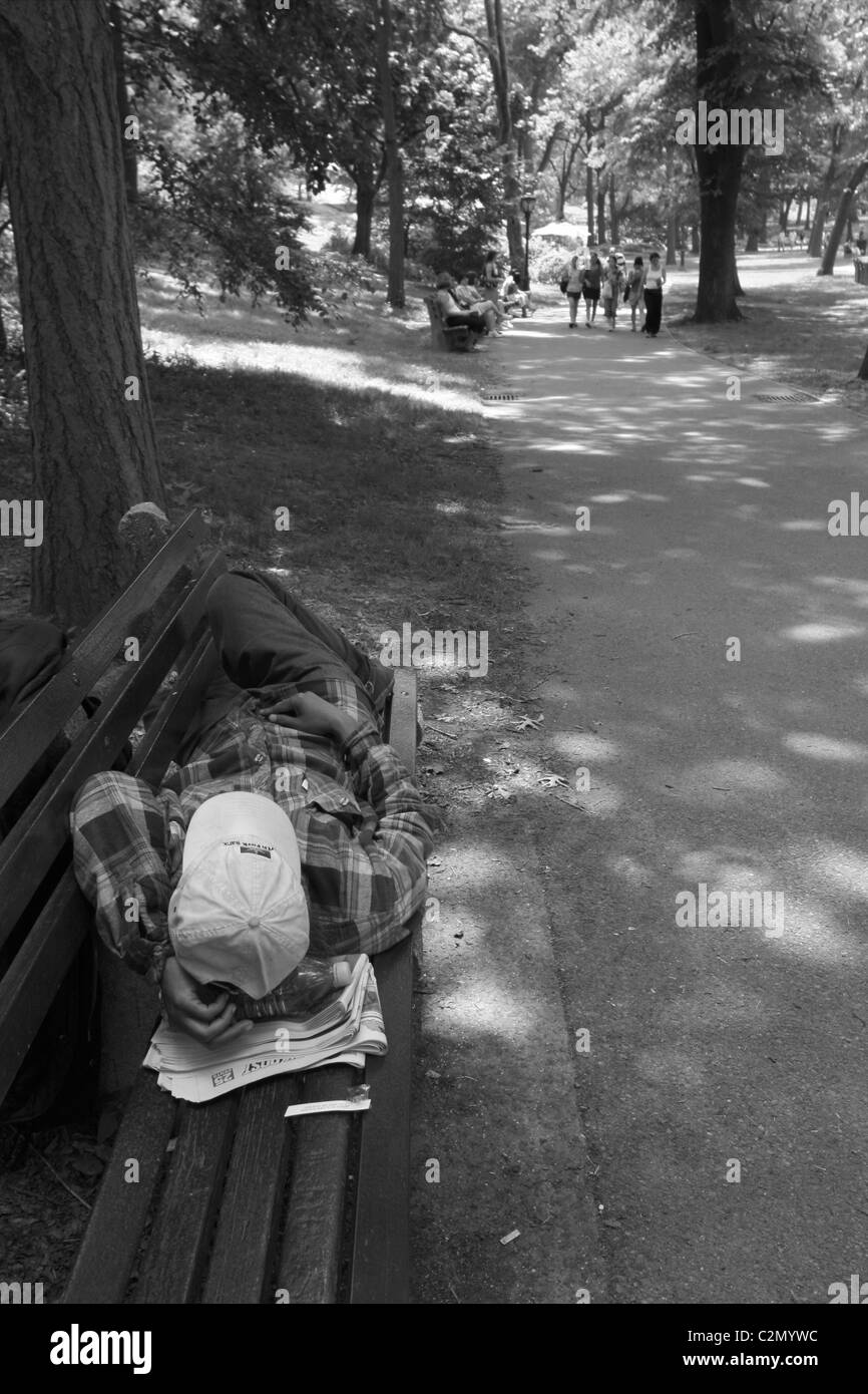 Mann schläft auf der Bank im Central Park in New York Stockfoto