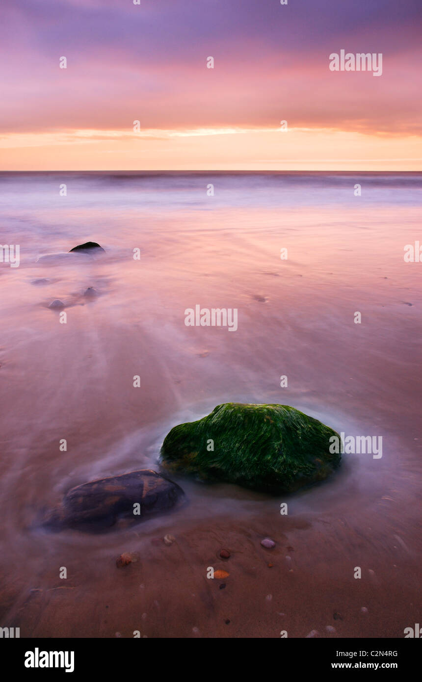 Ruhigen Sonnenaufgang über dem Meer mit zwei Felsen im Vordergrund. Stockfoto
