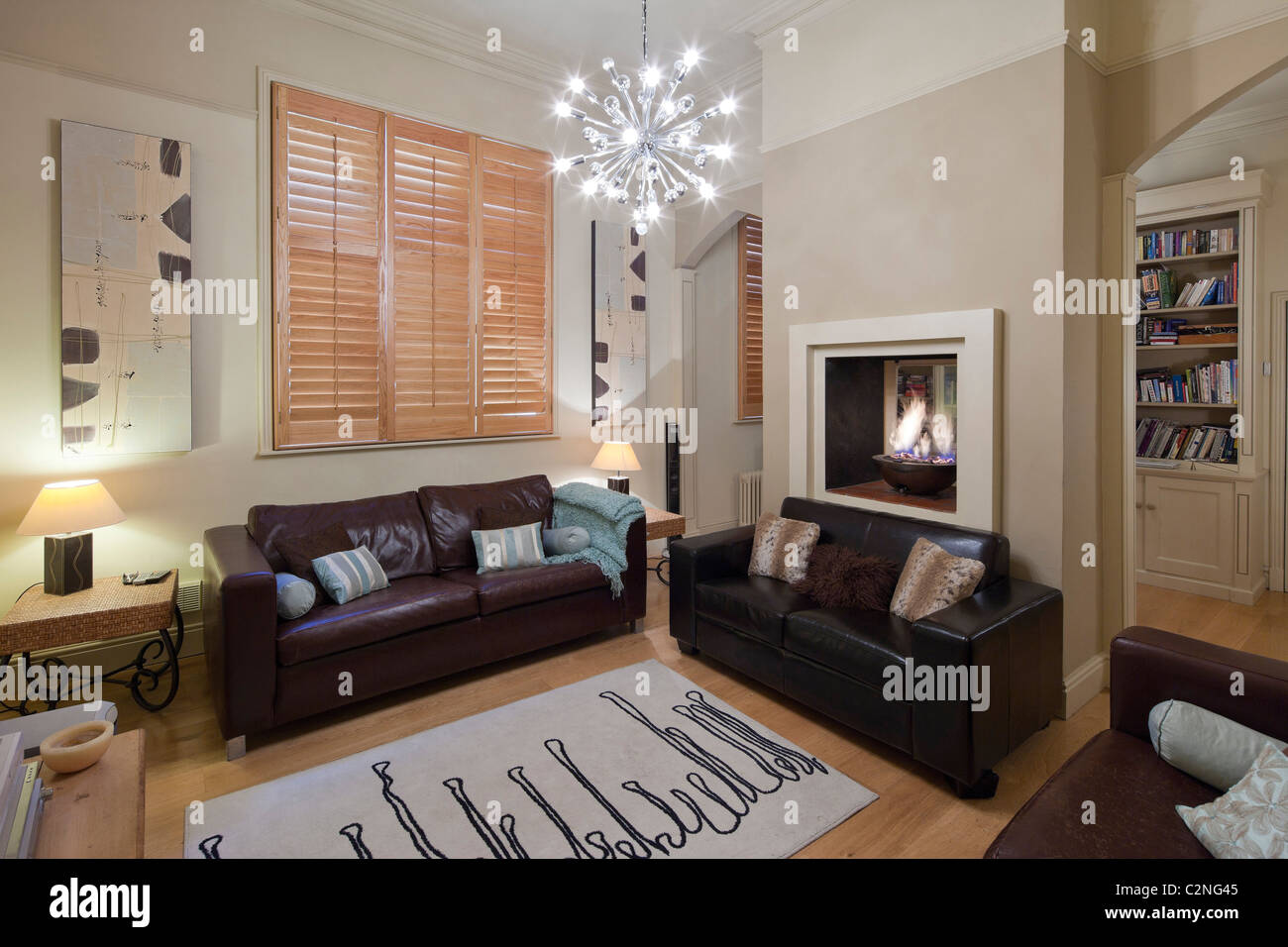 Neutrale Familie Wohnzimmer mit Holzboden, hölzernen Fensterläden & Ledersofas Stockfoto