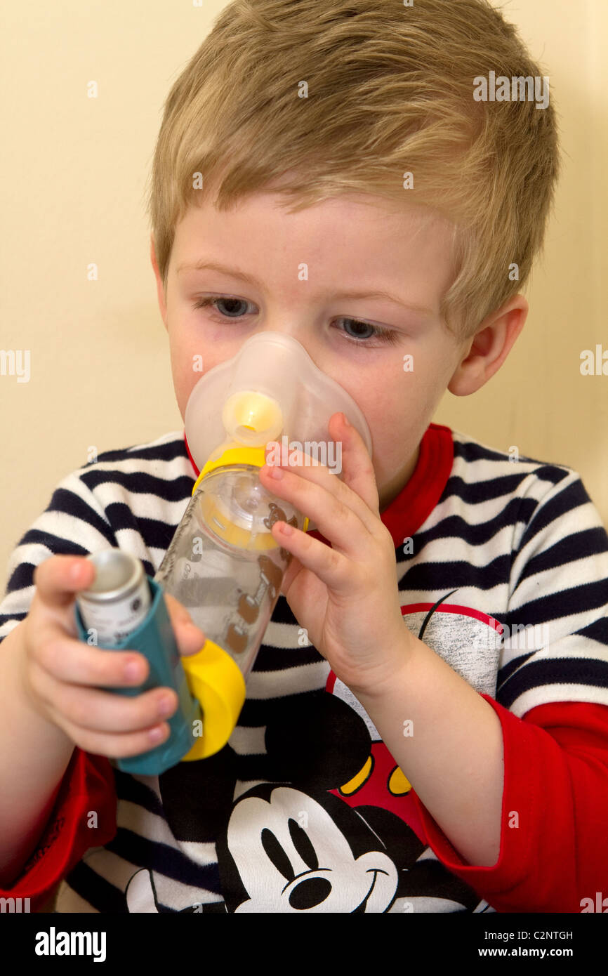 Kleiner Junge mit einem Asthma-Inhalator mit Abstandshalter. Stockfoto