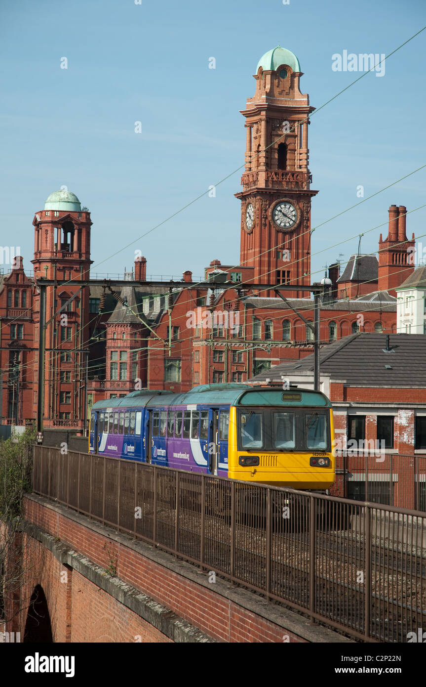 Northern Rail Train Reisen durch das Zentrum von Manchester, das Palace Hotel im Hintergrund. Stockfoto