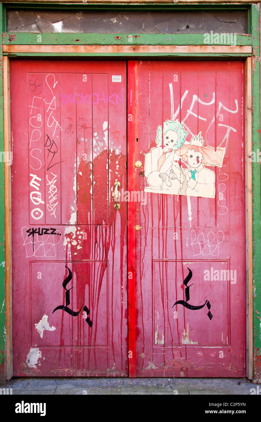 Ein paar rote Holztüren mit Graffiti direkt an der Brick Lane London, E1, UK Stockfoto