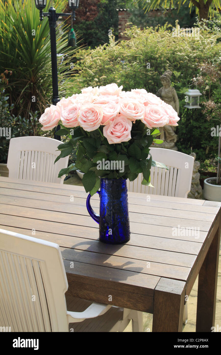 Eine schöne Vase mit Rosen auf einem Terrassentisch an einem sonnigen Tag Stockfoto