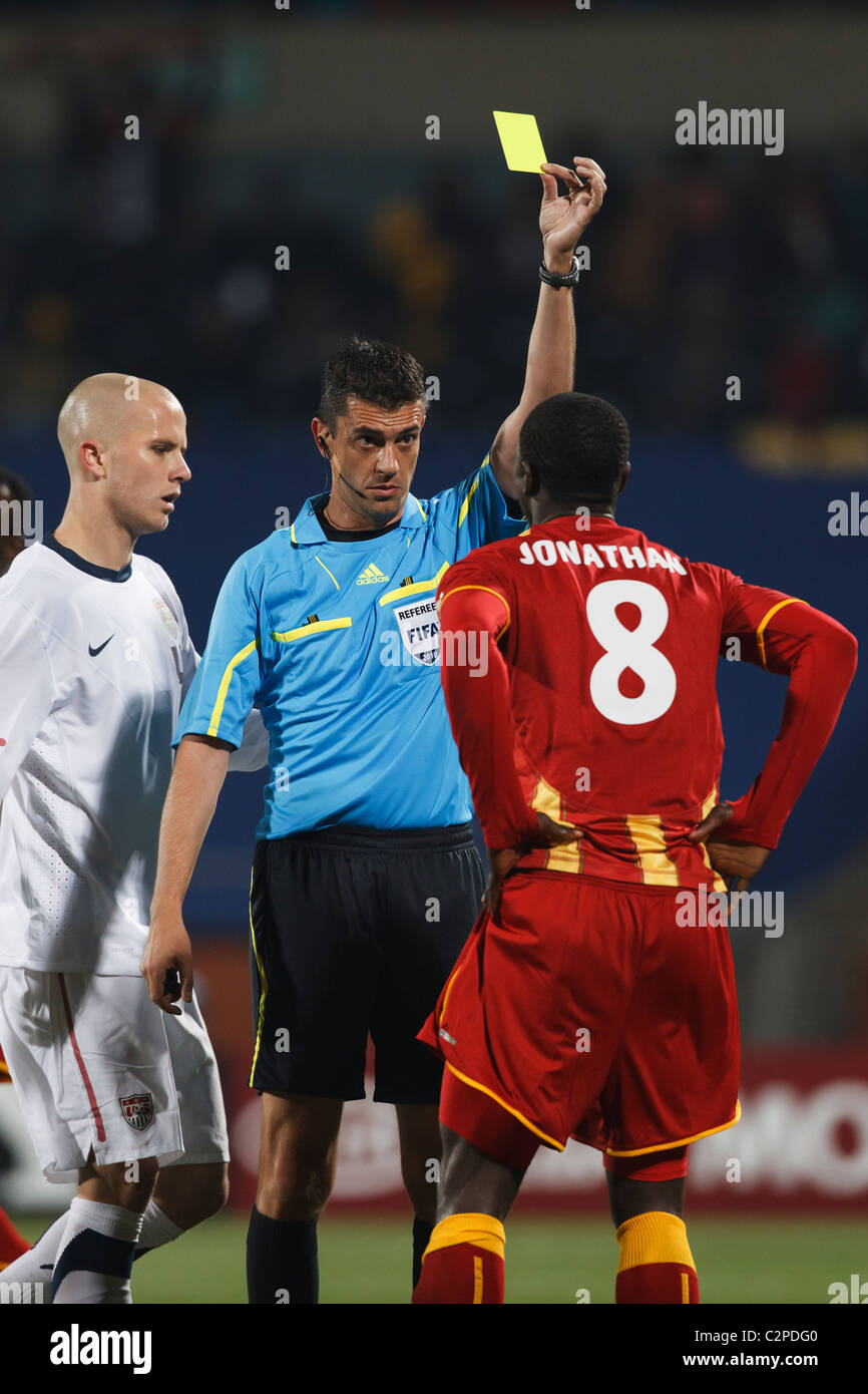 Schiedsrichter Viktor Kassai gibt eine gelbe Karte Vorsicht an Jonathan Mensah von Ghana im 2010 World Cup Spiel gegen die USA. Stockfoto