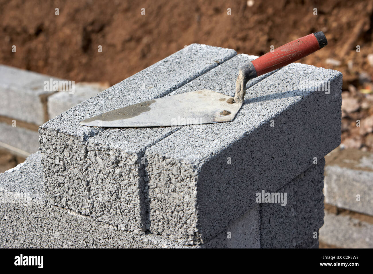 Maurerarbeiten Kelle auf einen Haufen von halben Zementblöcke Brise Bau einer Stützmauer Block im Vereinigten Königreich Stockfoto