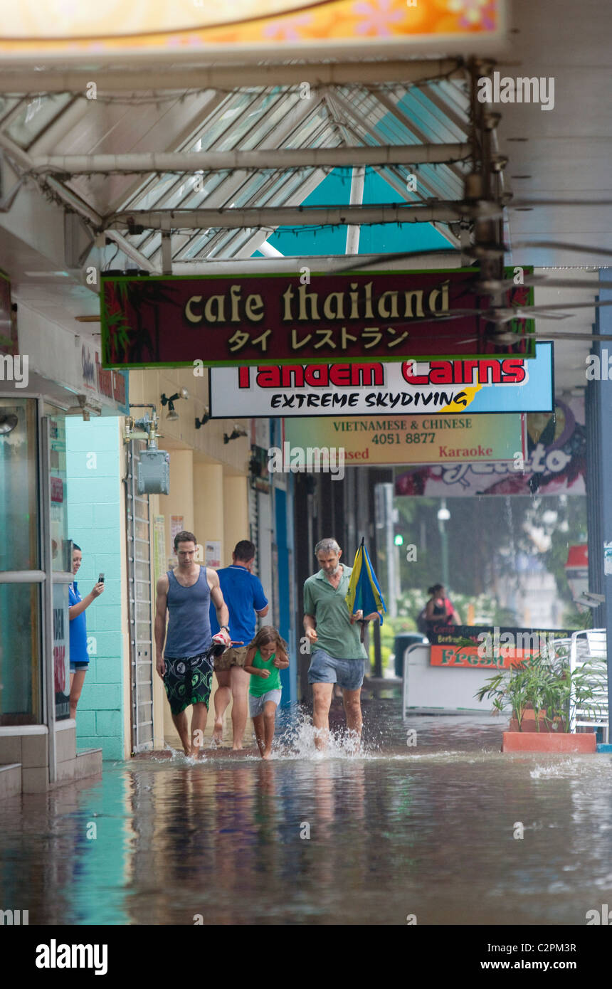 Einheimischen übergeben Geschäfte aufgrund von Starkregen überflutet und der König der Gezeiten auf Aplin Street. Cairns, Queensland, Australien Stockfoto
