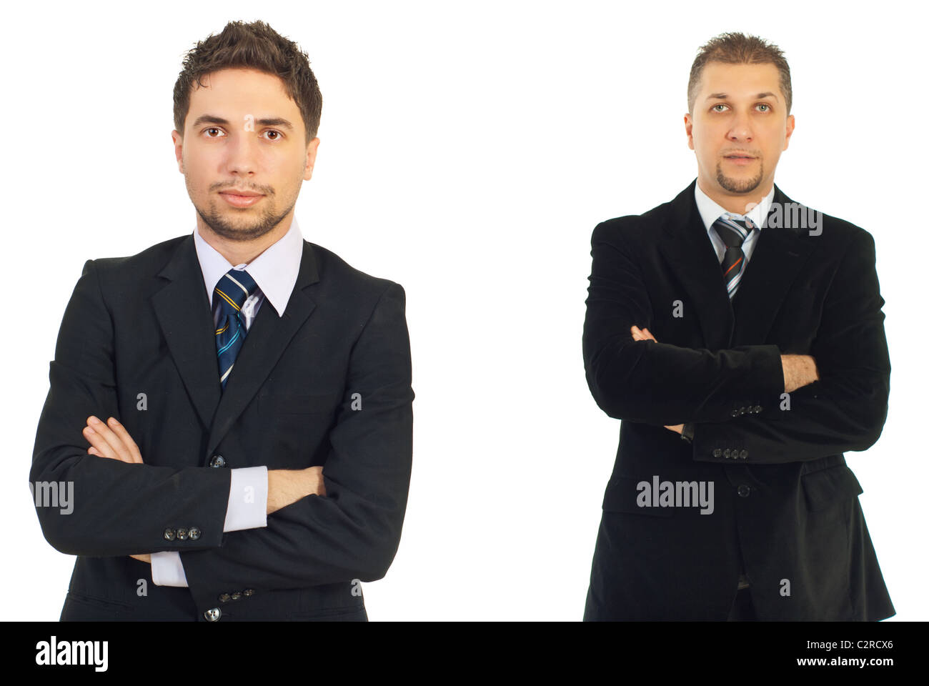 Junger Geschäftsmann mit verschränkten Armen vor Kamera und seine Mitte Erwachsenen Kollegen Mann im Hintergrund Stockfoto