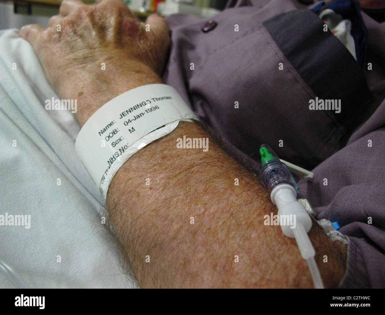 ältere Menschen mans Arm mit Namensschild und Tropf im Krankenhaus Stockfoto
