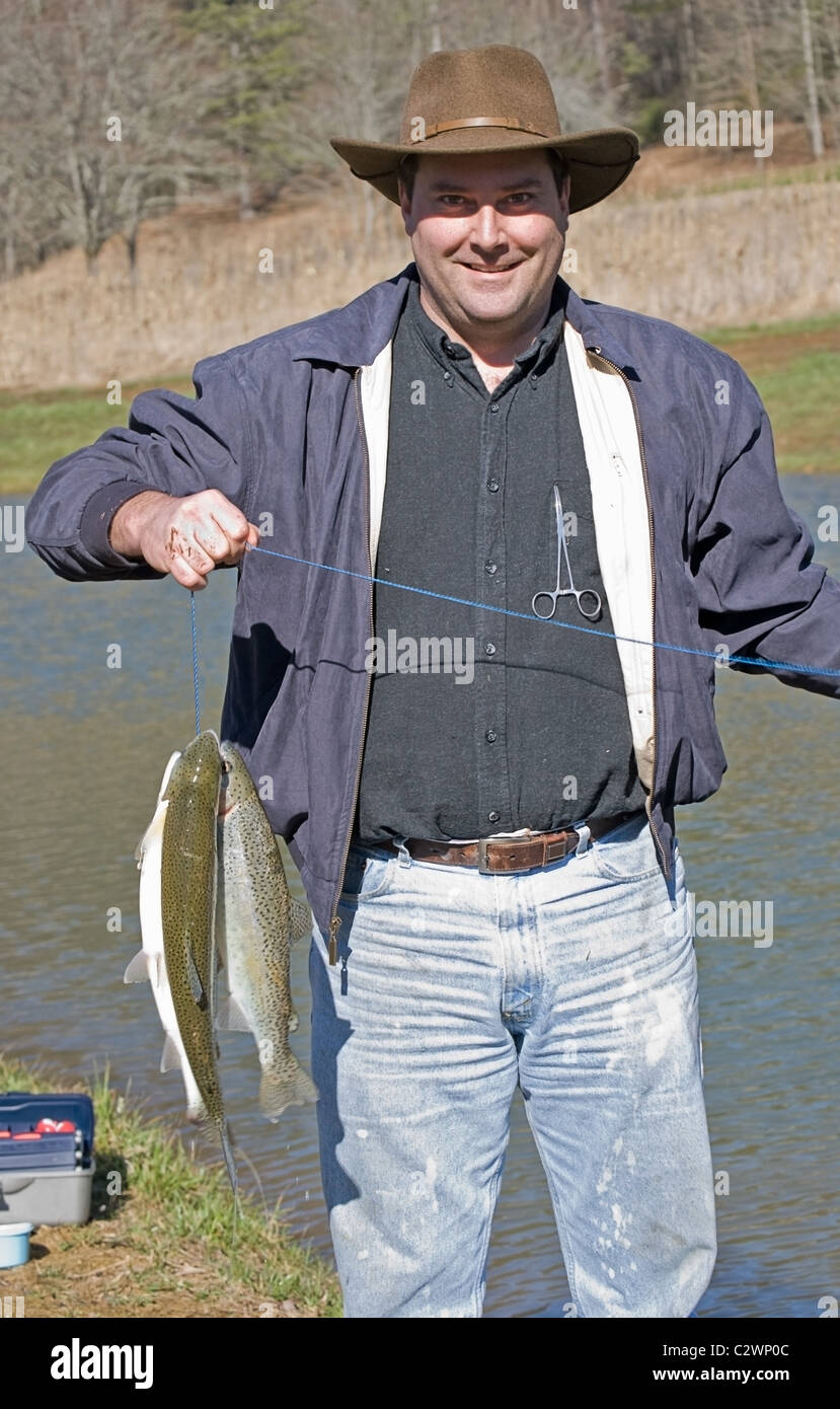 Mann an einem Teich mit seiner Wange frische Regenbogenforellen. Stockfoto