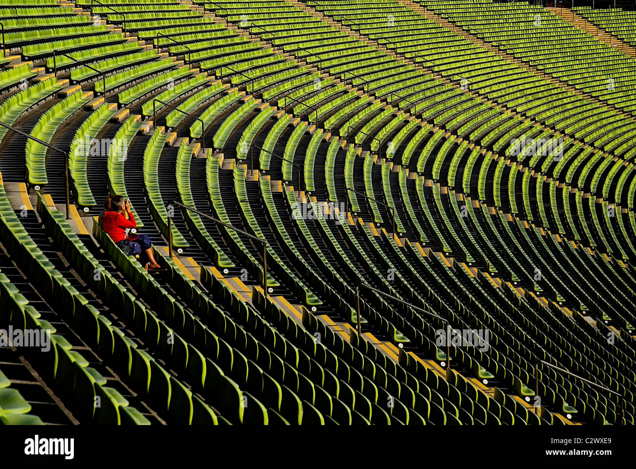Deutschland Bayern München Olympiastadion gebogenen Abschnitt hell grüne Sitzgelegenheiten mit einzelnen Person sitzen. Stockfoto
