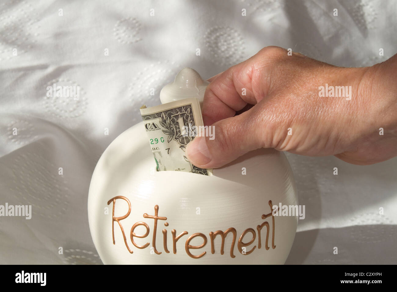 Ein Mann, eine amerikanische 1 Dollar Bill in ein "Einsparungen tirement'-Container. Das Bild leuchtet durch Fenster Licht Stockfoto