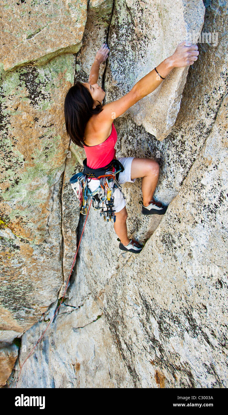 Weiblichen Rock Climber kämpft für ihren nächsten Griff am Rande einer steilen Klippe. Stockfoto