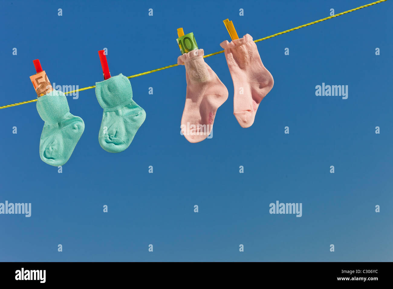 Baby Socken auf der Wäscheleine mit Euro-Banknoten Stockfoto