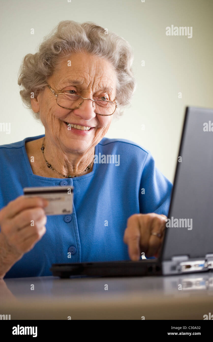 Lächelnde ältere Frau mit Kreditkarte und laptop Stockfoto