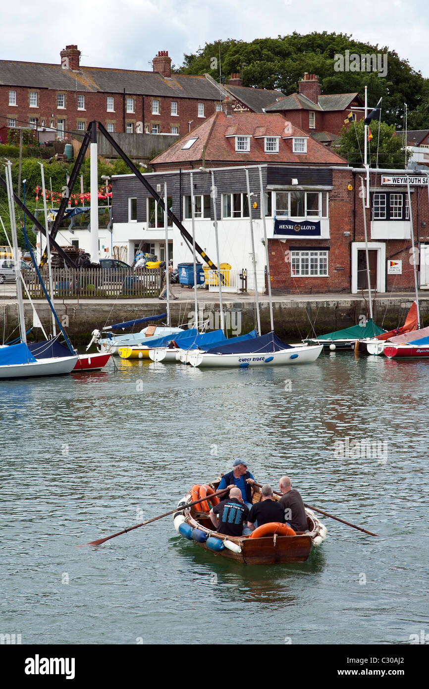 Kleines Boot rudern über Wemyouth Hafen, Dorset, England, Großbritannien Stockfoto