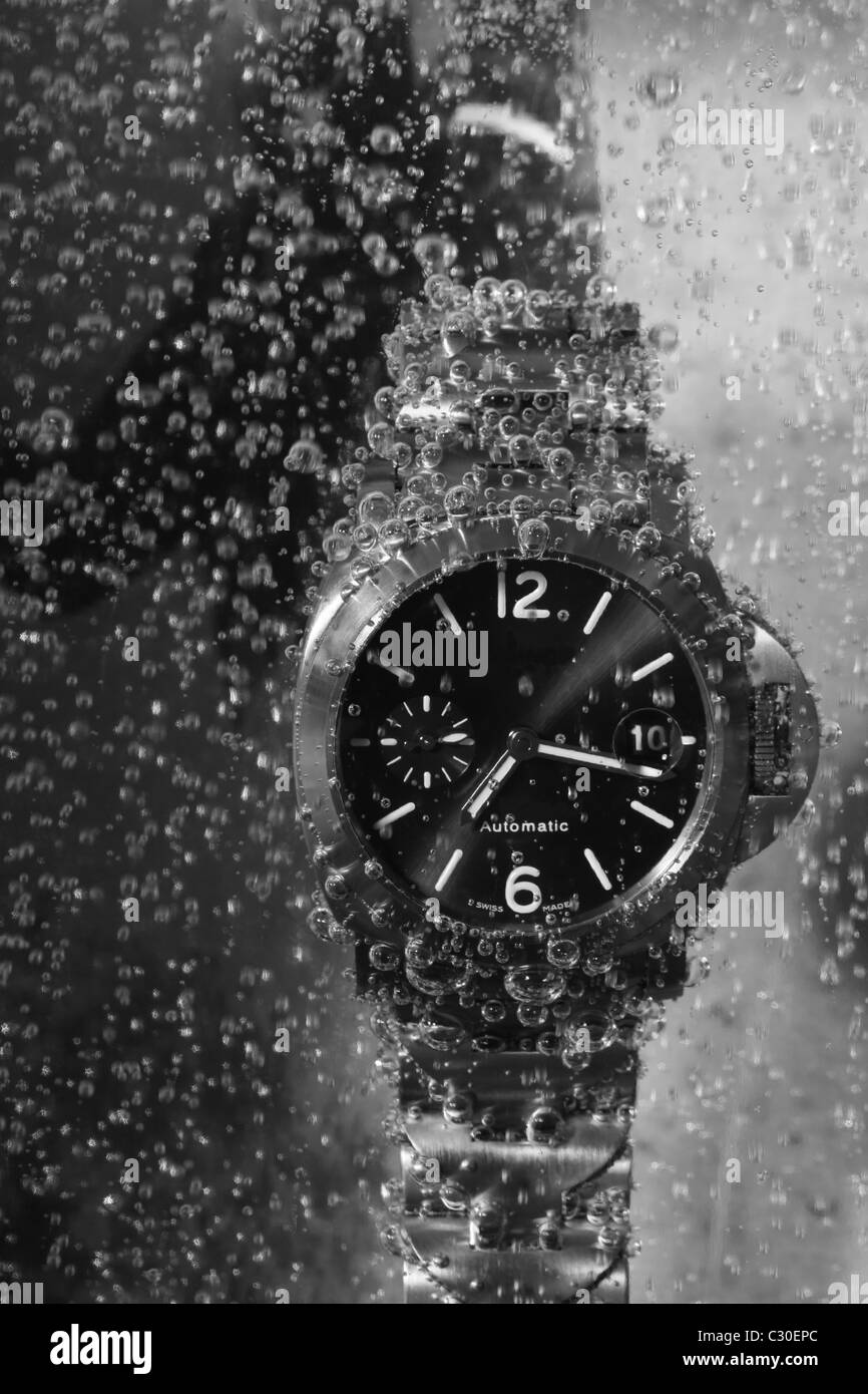 Eine Uhr, die untergetaucht im Wasser mit einem Taucher Charakter hinter Stockfoto