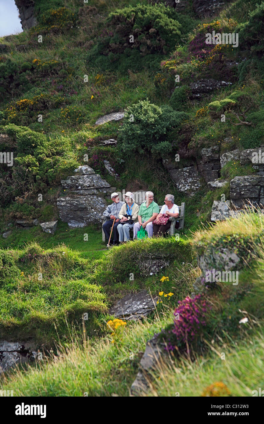 Eine Gruppe von älteren Touristen ruht auf einer Bank auf dem South West Coast Path in der Nähe von das Tal der Felsen in North Devon England UK Stockfoto