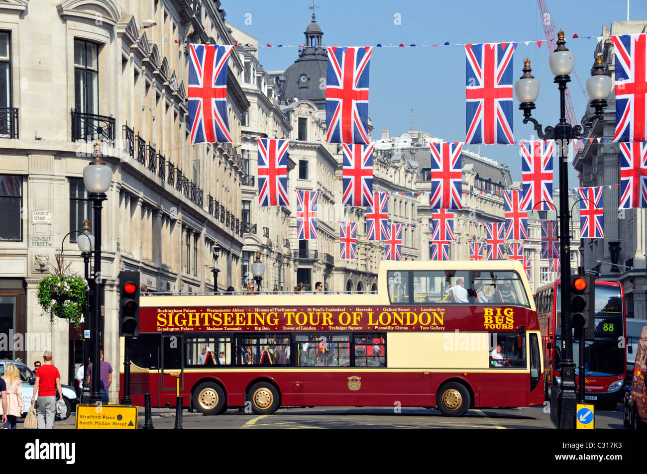 Flaggen mit Sightseeing-Tour durch London Werbung auf der Seite Offener Doppeldecker-Großbus, der zur Regent Street wird Unter Union Jack Flagge veraunting UK Stockfoto