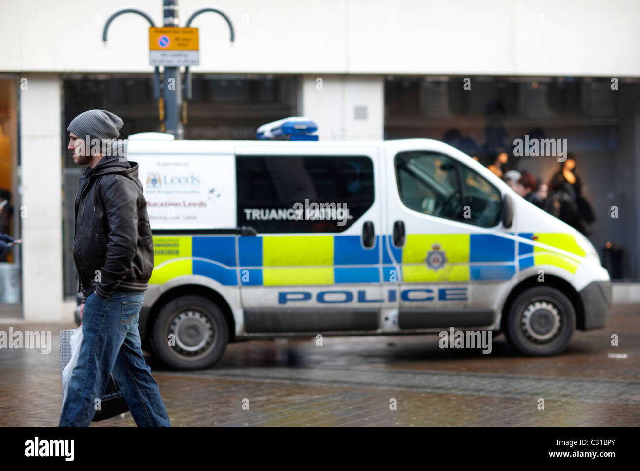 Schulschwänzen Polizeiwagen in Leeds mit Mann vorbeigehen Stockfoto