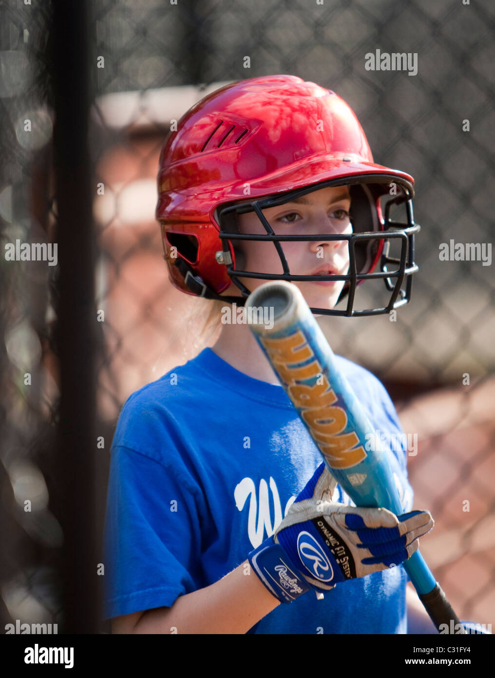 Junges Mädchen trägt einen Helm und hält einen Softball-Schläger Stockfoto