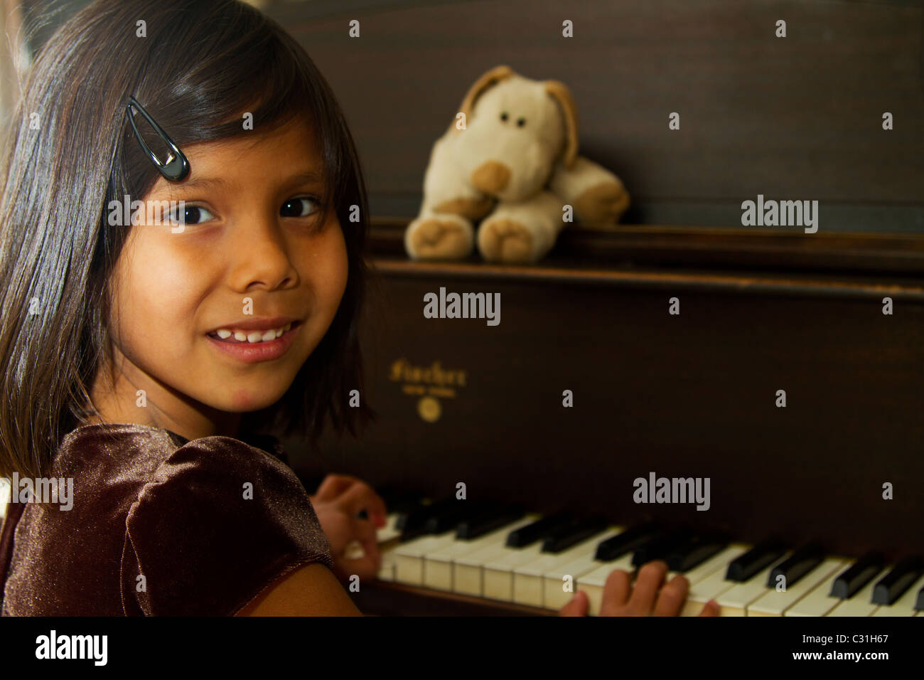 Junges Mädchen das Klavierspiel für ihr Stofftier Stockfoto