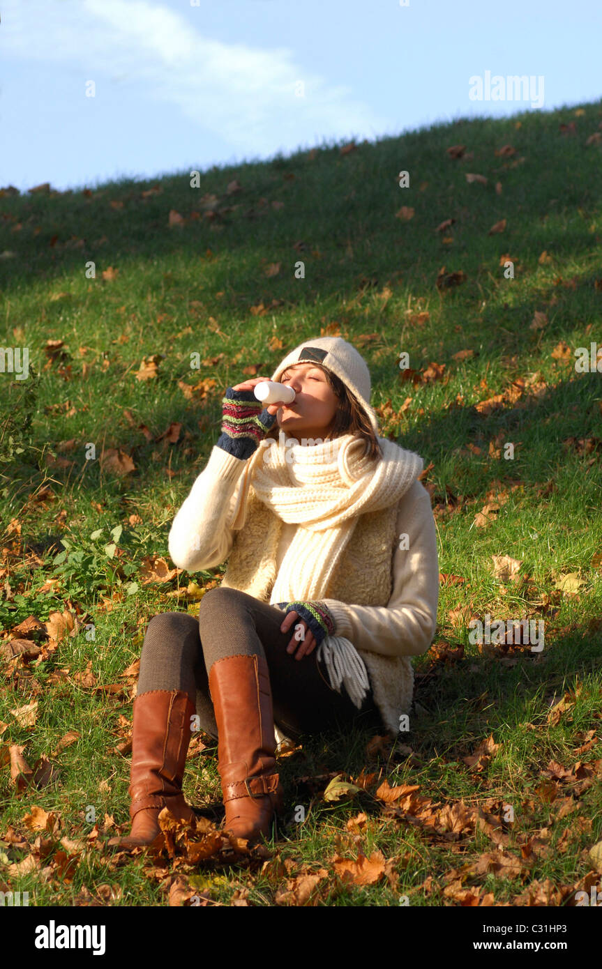 STÄRKUNG DES IMMUNSYSTEMS. JUNGE FRAU SCHLÜRFEN EINEN JOGHURT MIT MILCHKULTUREN. Stockfoto