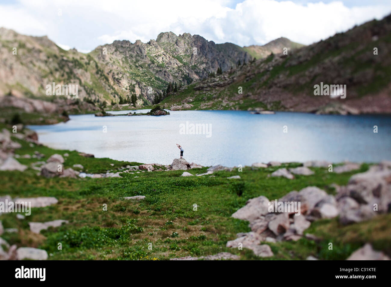 Eine junge Frau balanciert auf einem Felsen beim Yoga am Rande eines Bergsees in Colorado. Stockfoto