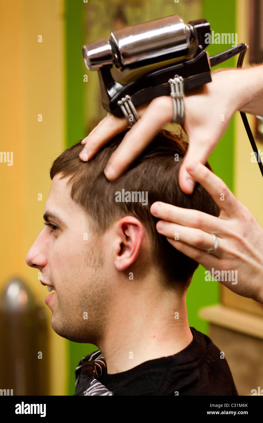 Ein Mann bekommt eine altmodische vibrierende Kopfmassage bei einem Friseur in Omaha, Nebraska. Stockfoto
