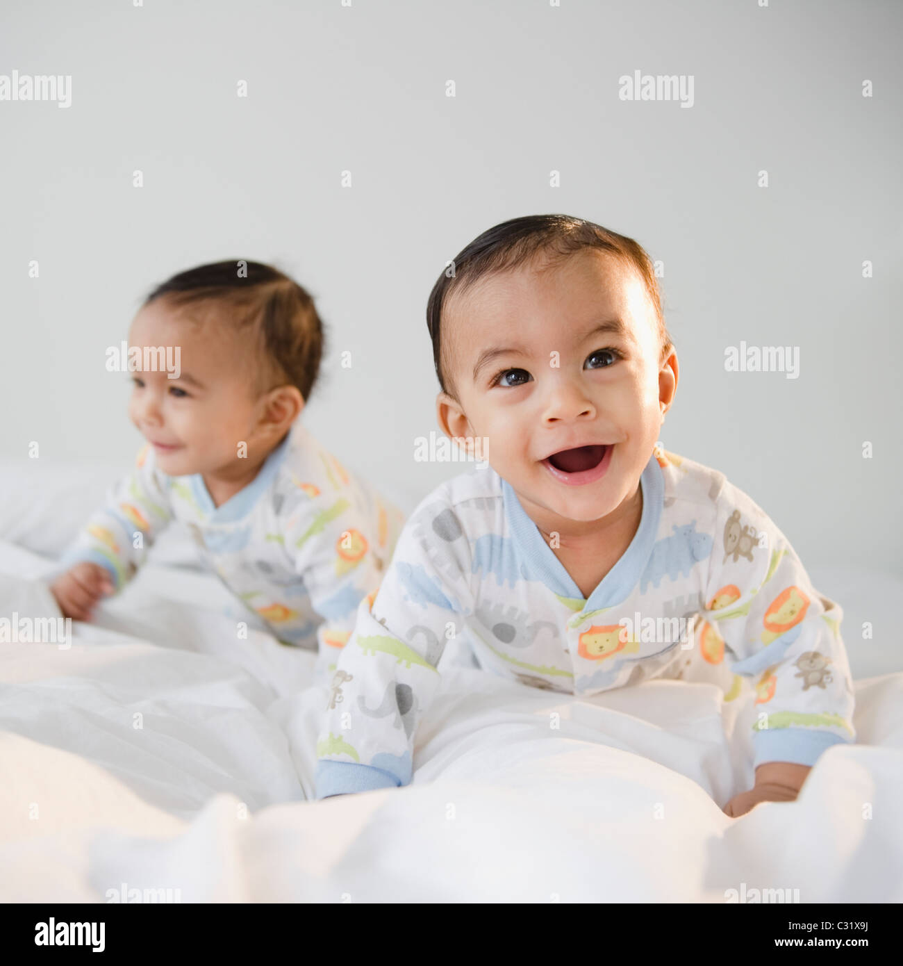 Gemischte Rassen Zwillinge krabbeln auf Bett Stockfoto