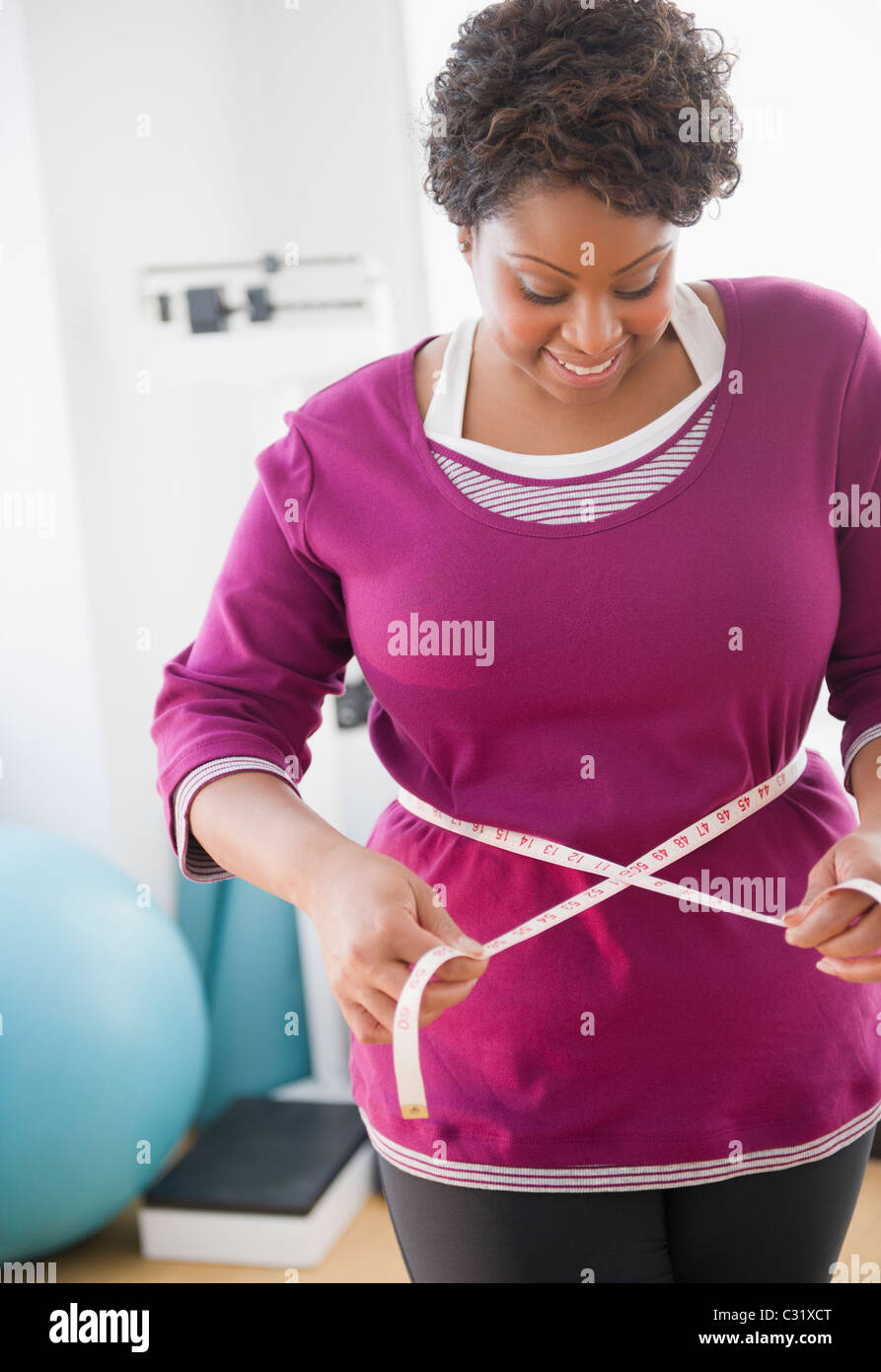 Afrikanische amerikanische Frau, die ihre Taille messen Stockfoto